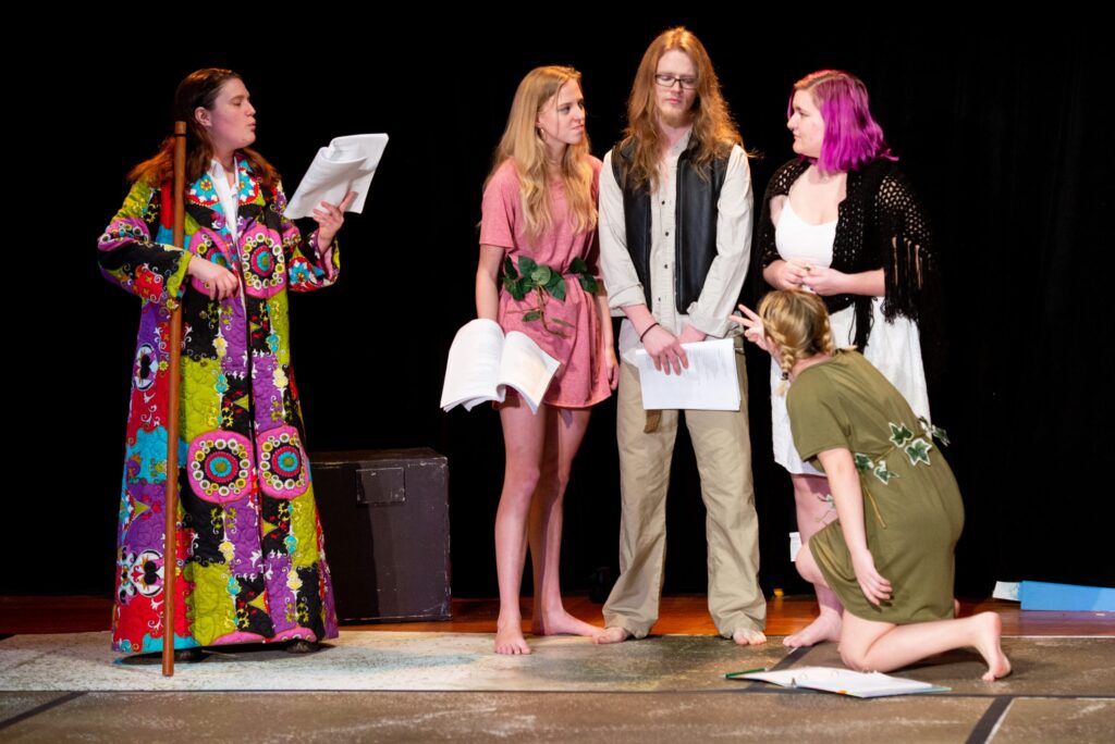 Five students rehearsing a play on the stage.