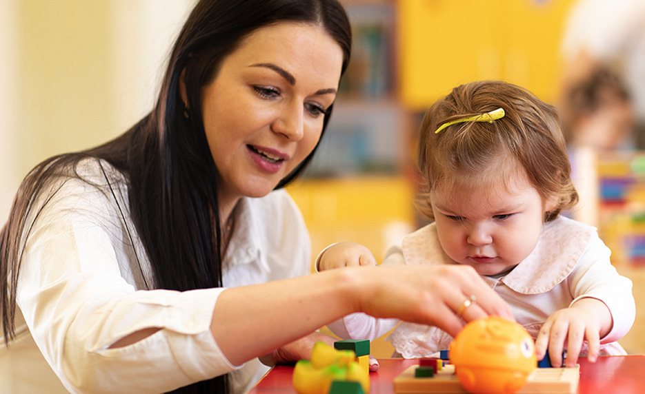 Teacher and very young child are counting with blocks