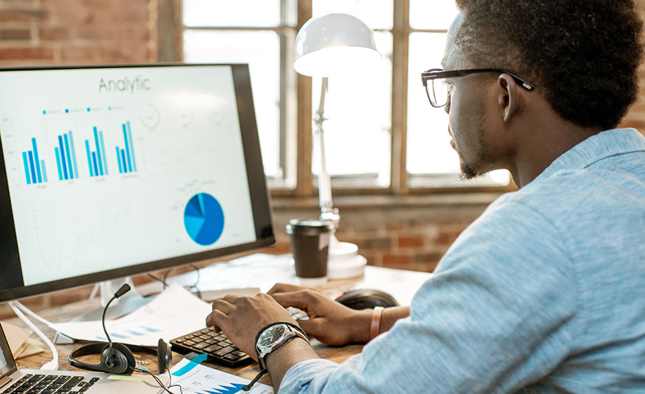 Man studies charts on a desktop computer at home.