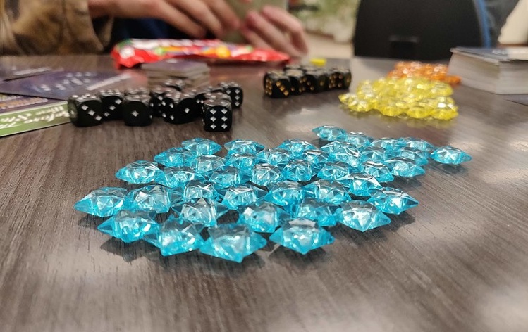 Board game pieces including teal tokens, black dice and yellow markers