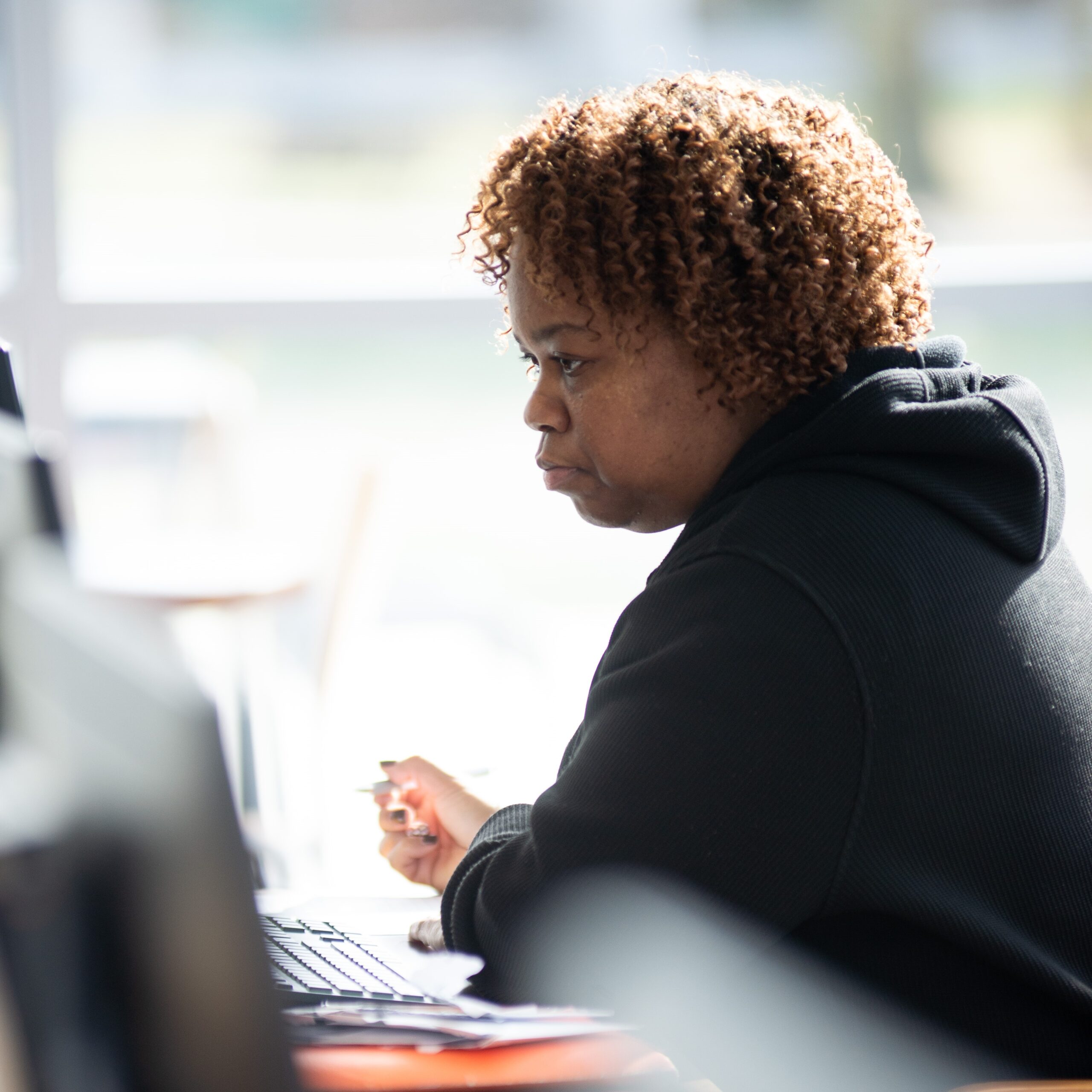 a female student takes written notes from what she sees on her computer screen