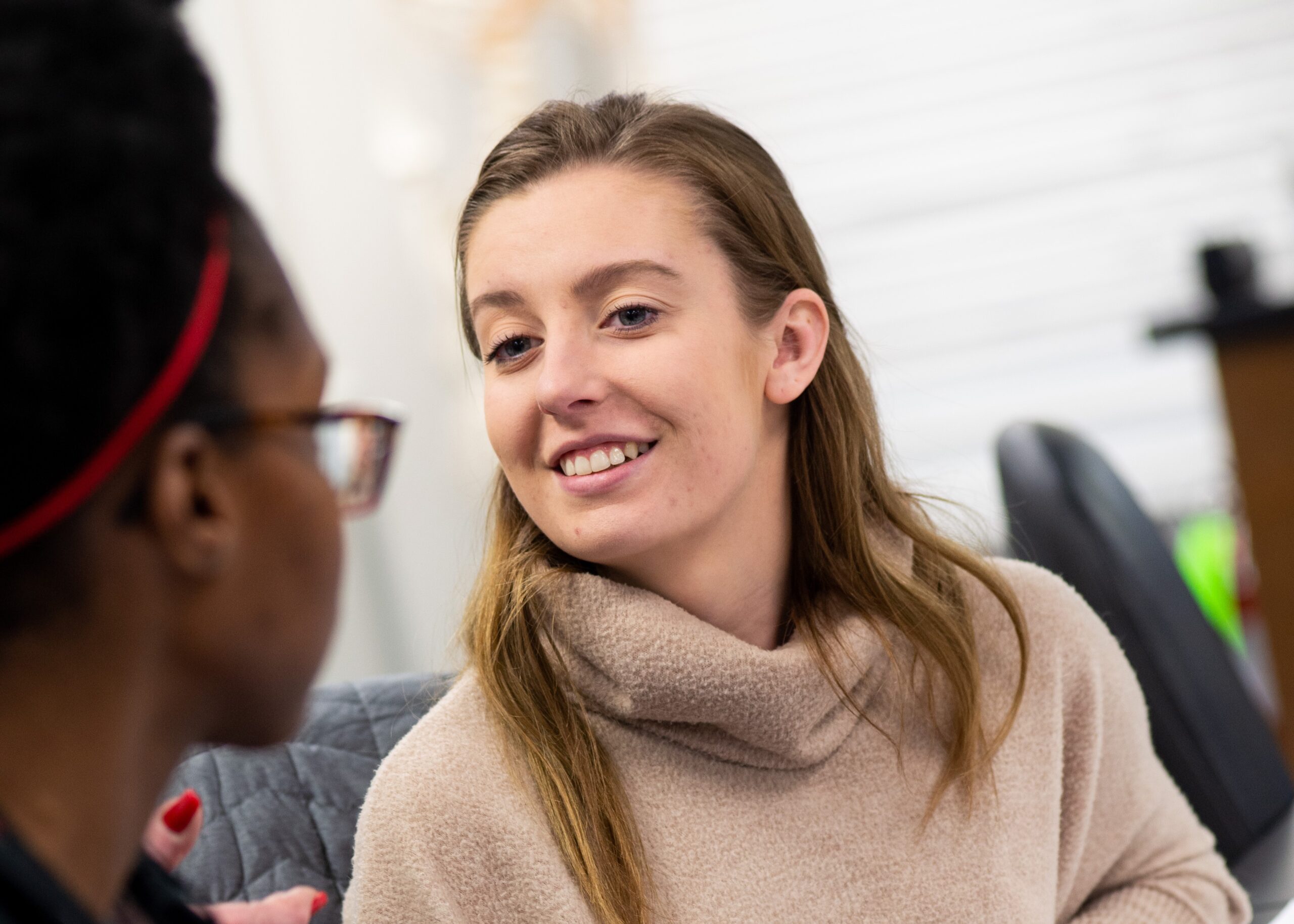 Landscape photo of one female student interacts with another in class