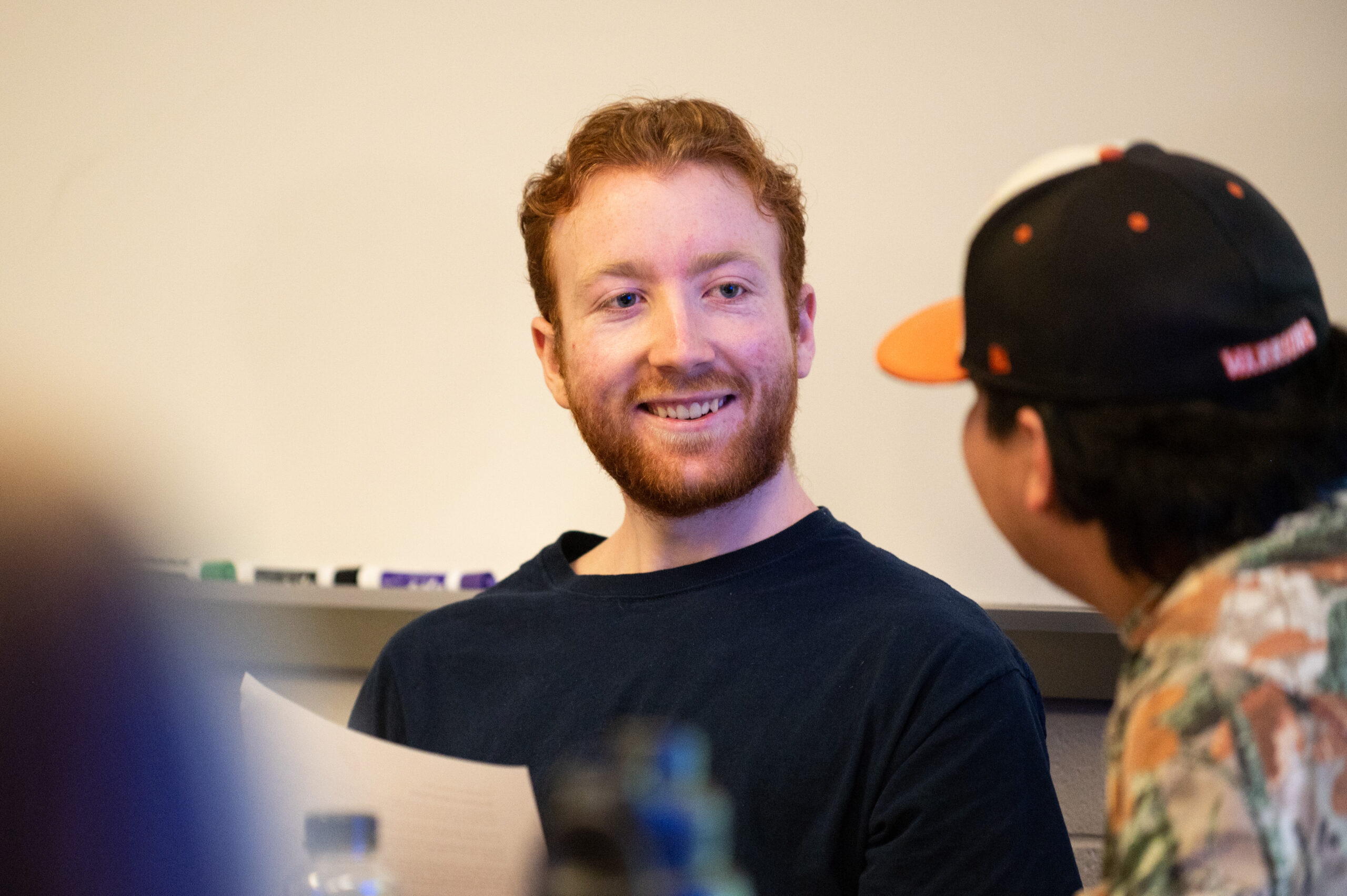 Male classmates smiling and talking during class.