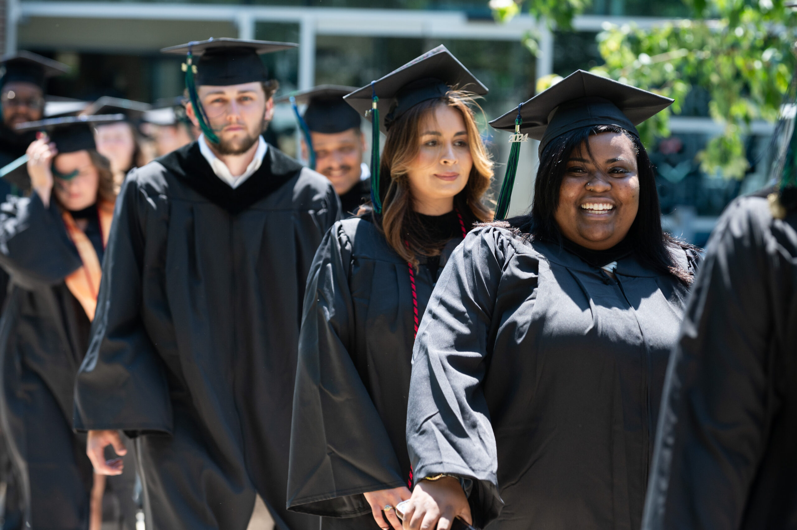 Line of graduates walking across campus on commencement day.