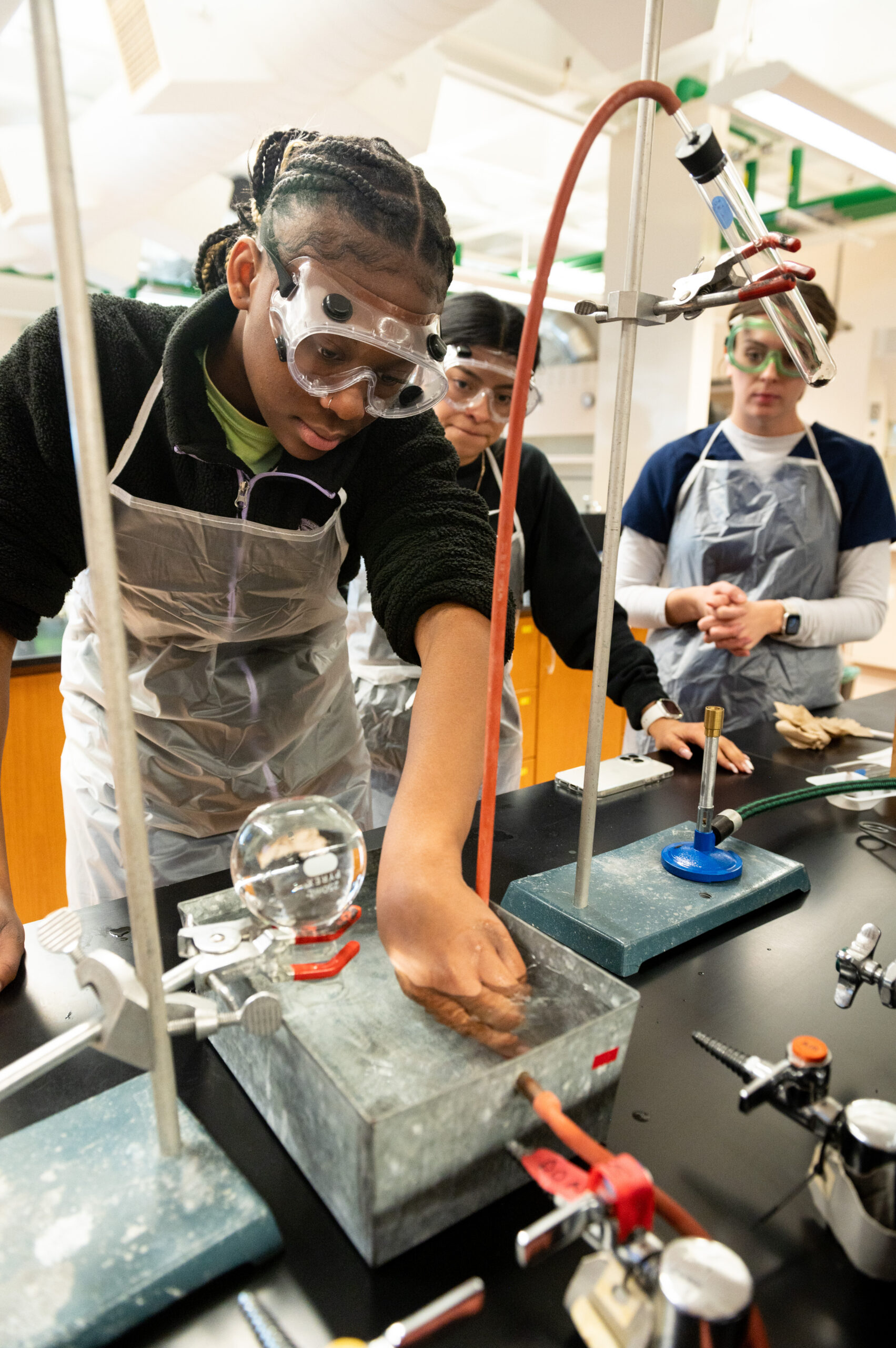 Three chemistry students conduct experiments in the lab.