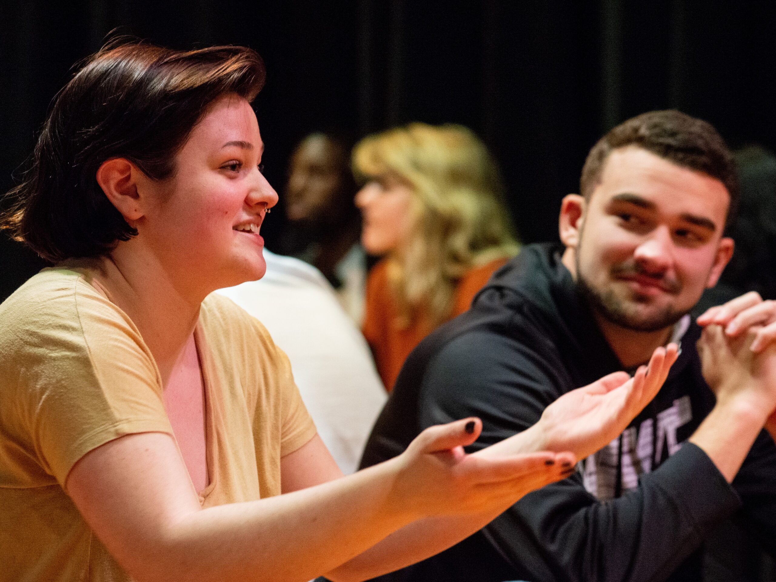 a student in a theatre class gestures with her hands while another student watches