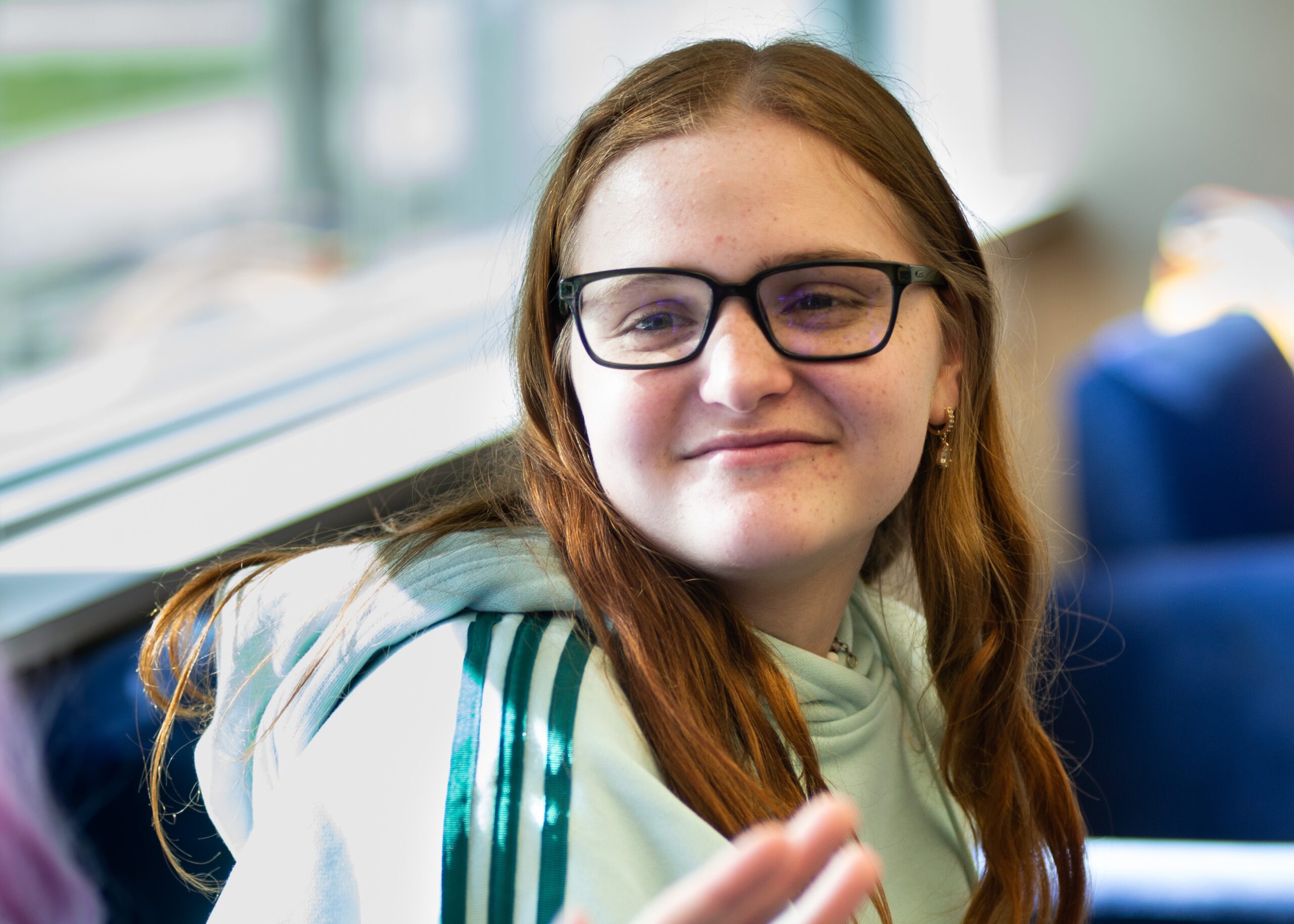 A college student smiles in a classroom.