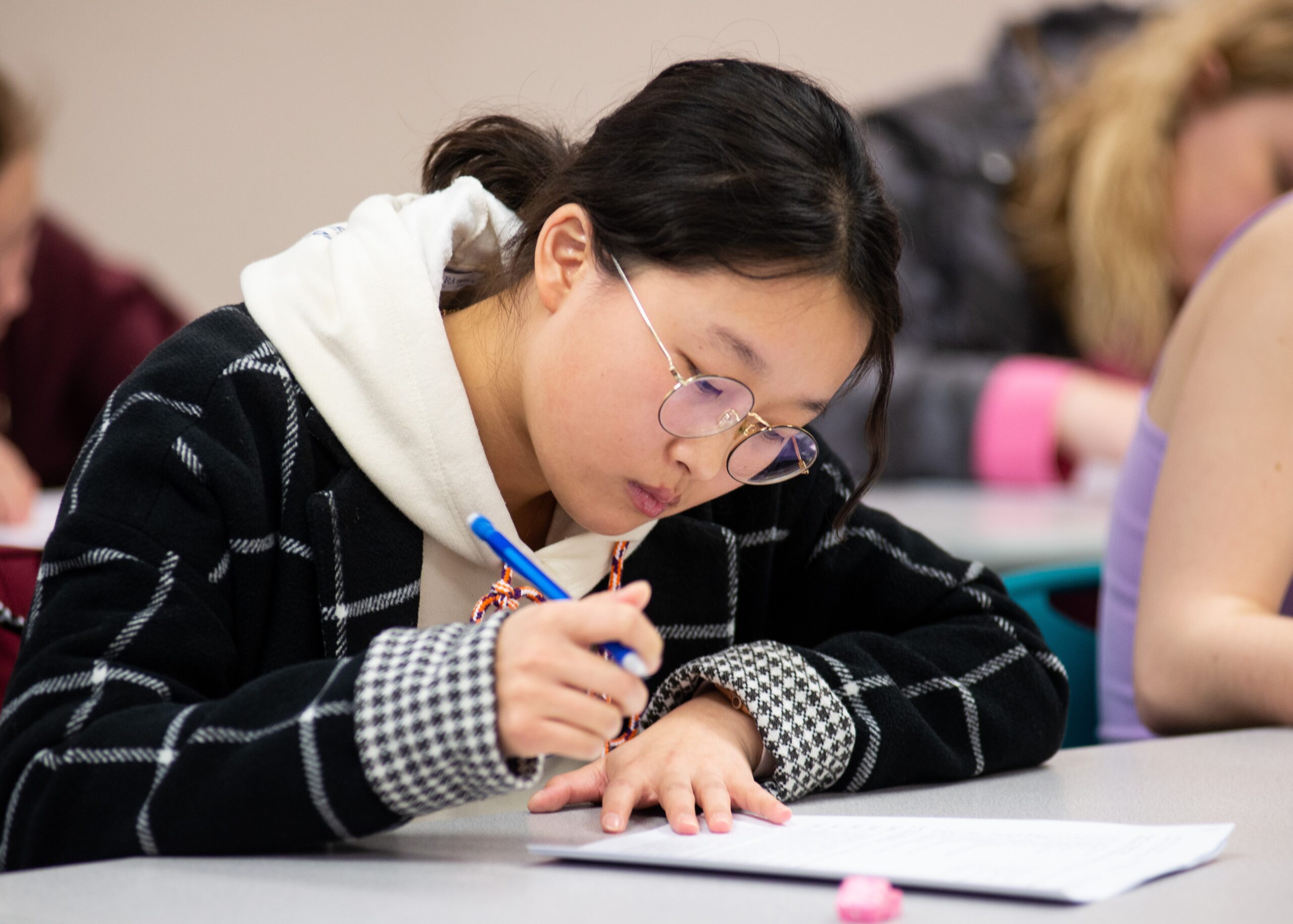 A young woman holding a pen works on an assignment.