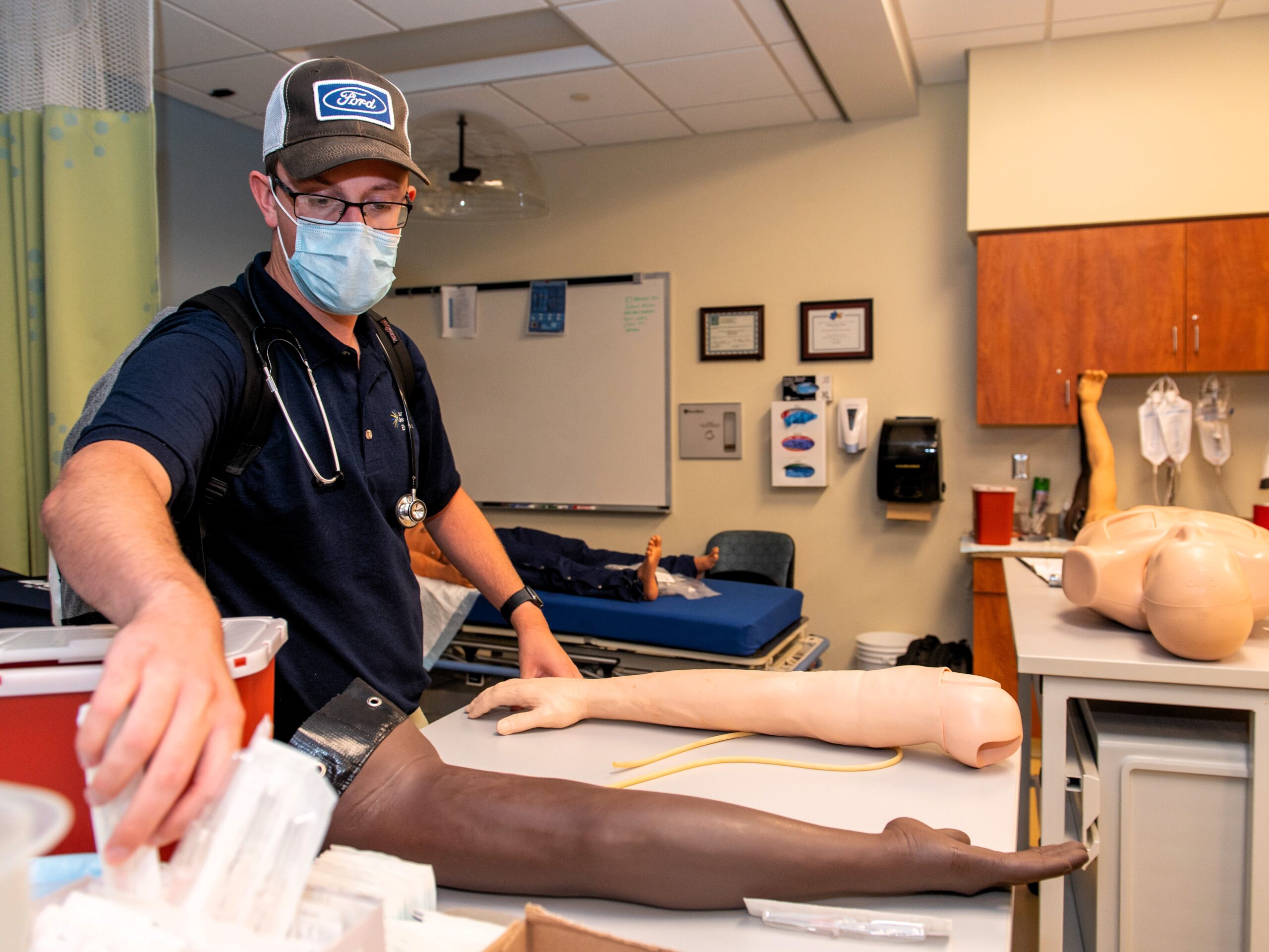 EMS student practicing on phlebotomy mannequins.