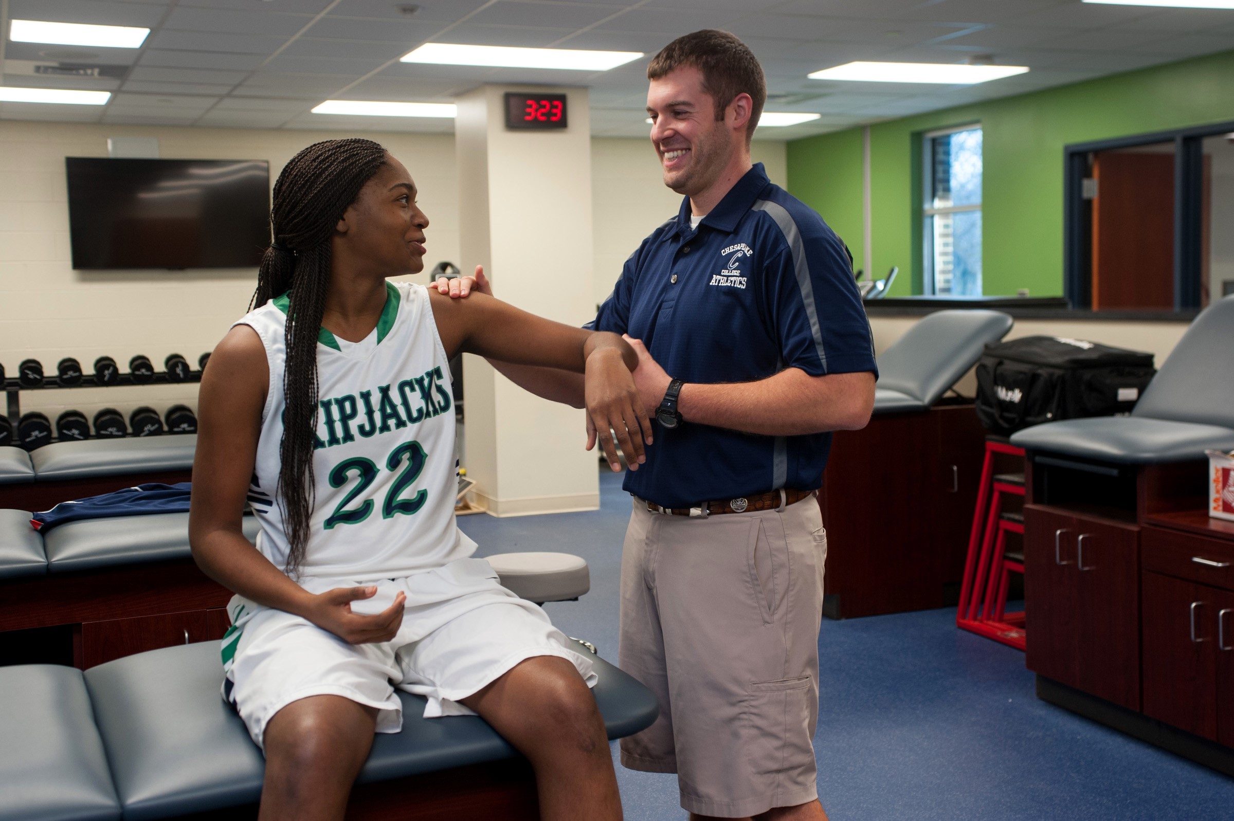 Exercise Science student examines arm of athlete on Women's basketball team.