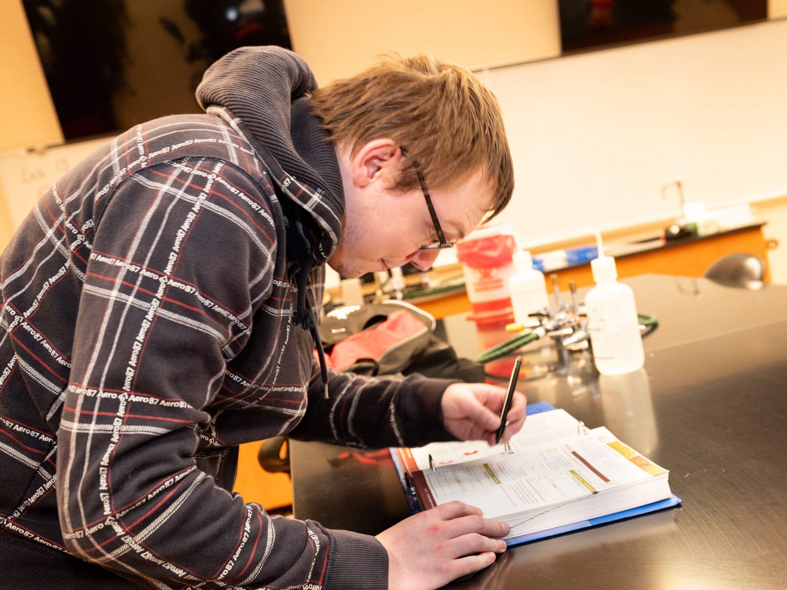 A student in a lab works on calculations from a textbook.