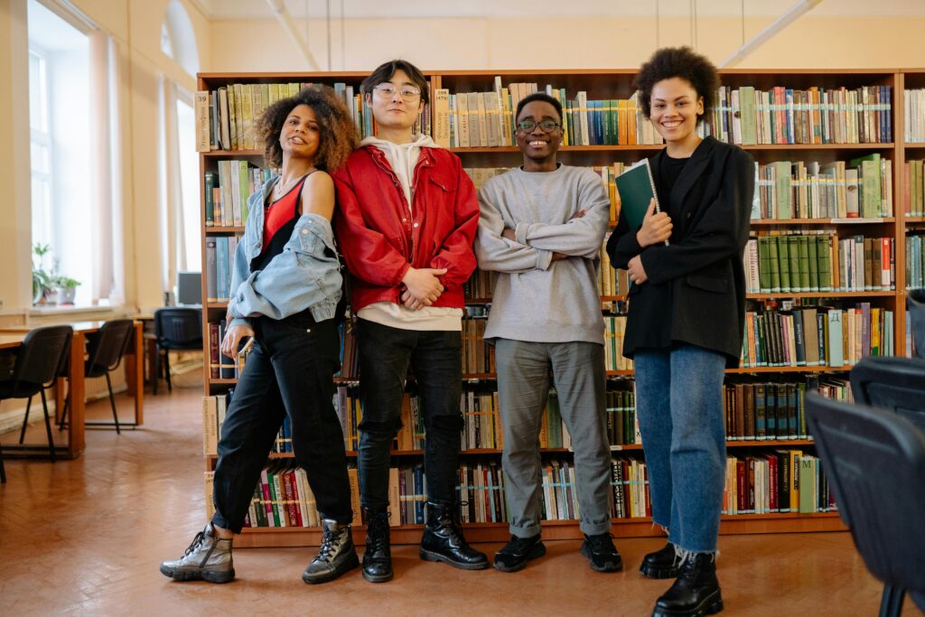 Student standing in front of book stacks in a library.