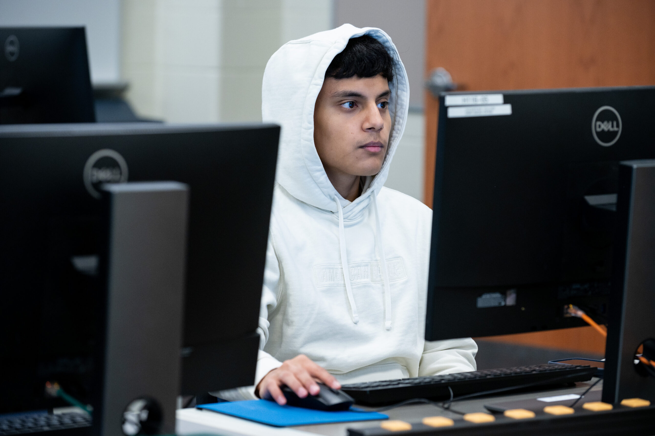 Student wearing white hoodie works at a lab computer in a computer class during the Fall 2023 semester