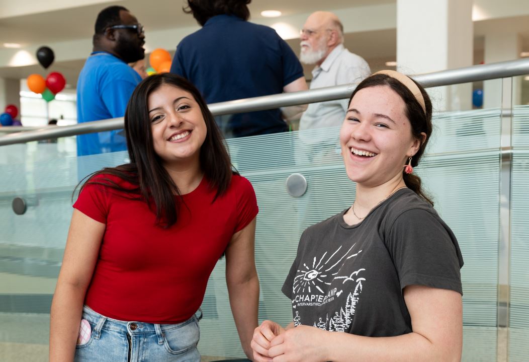 Two female students smiling and laughing toward the camera, taking part in a student organization event.