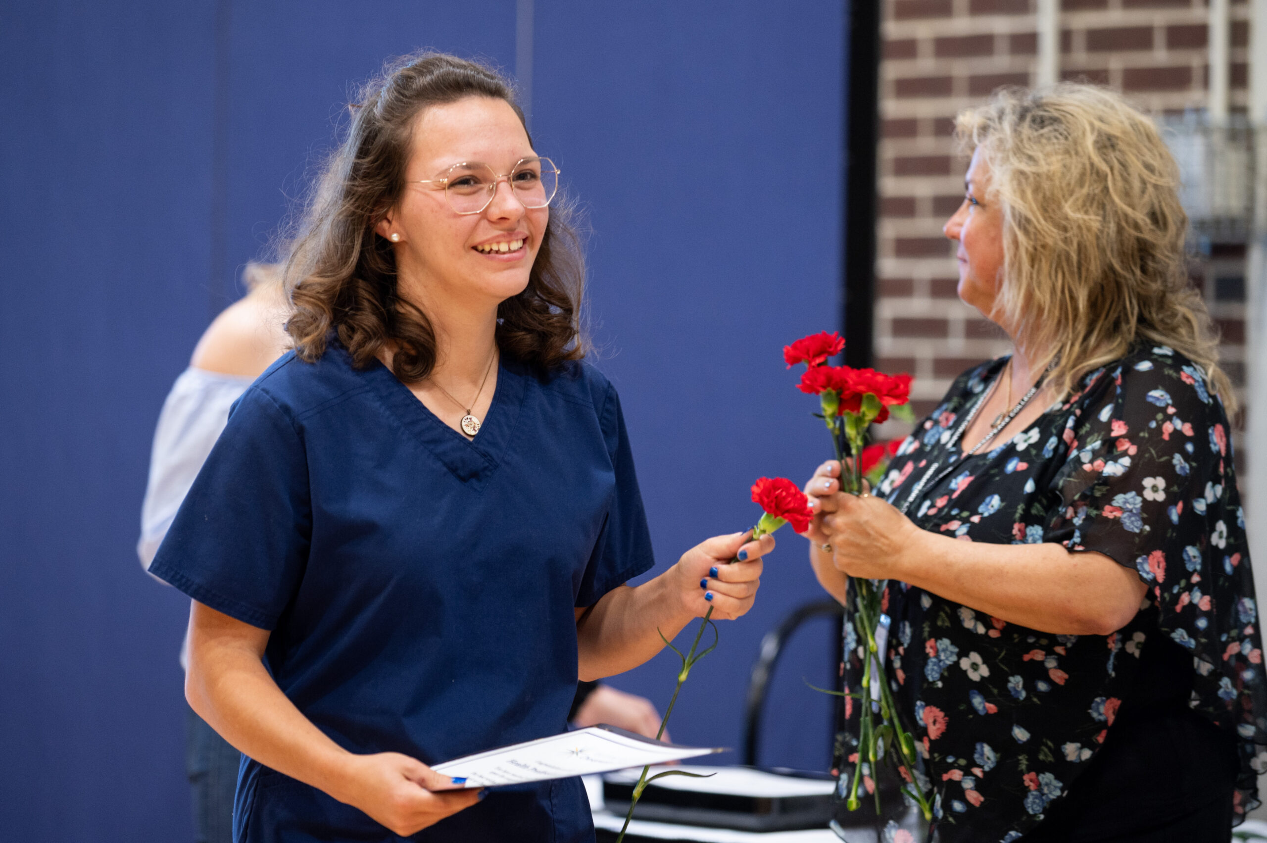 Dental Assistant graduate receives certificate and flower.