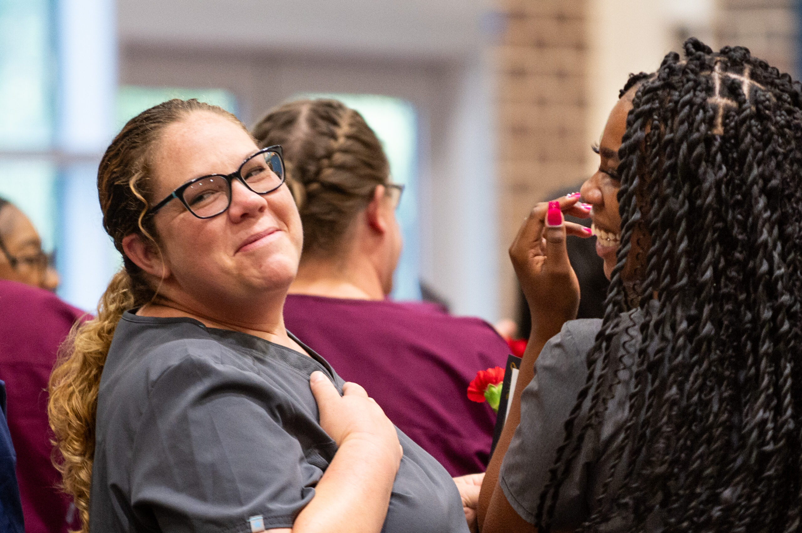 Health Profession student at graduation looking over shoulder with joy