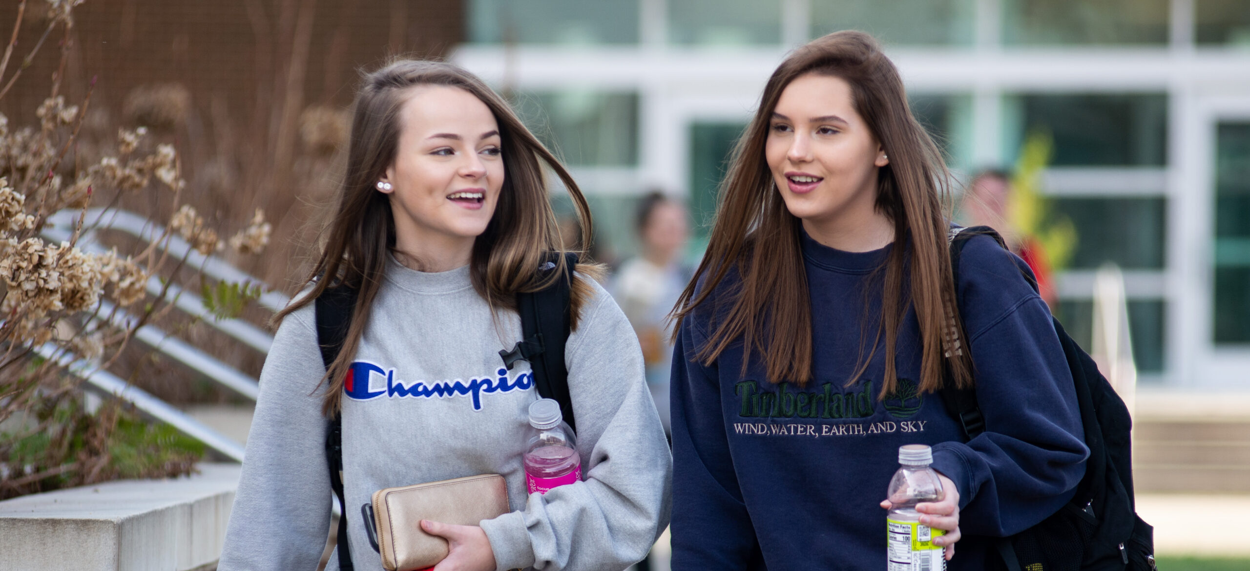 Two female students walk outside on campus.