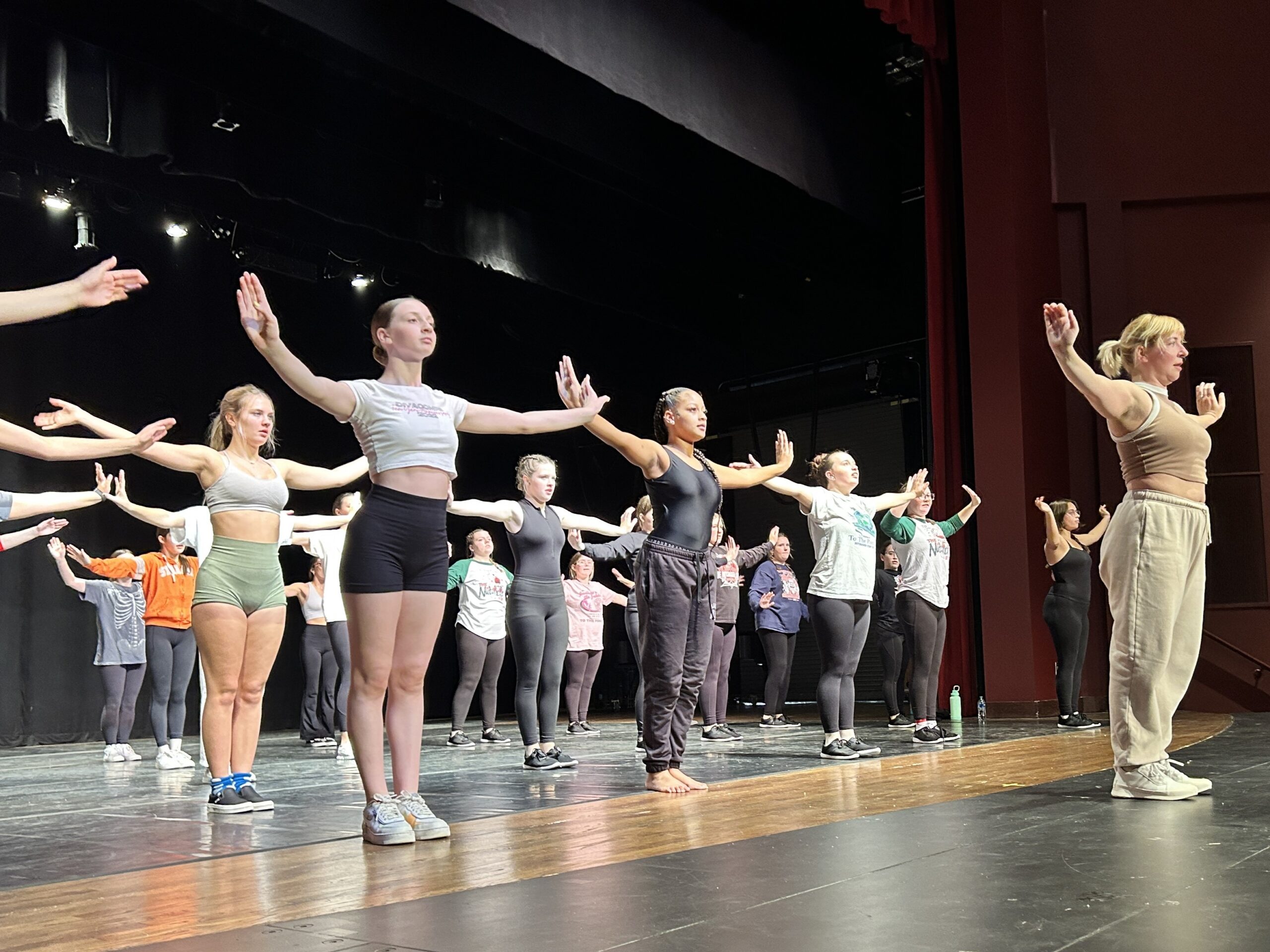 dance students form rows behind an instructor with arms outstretched