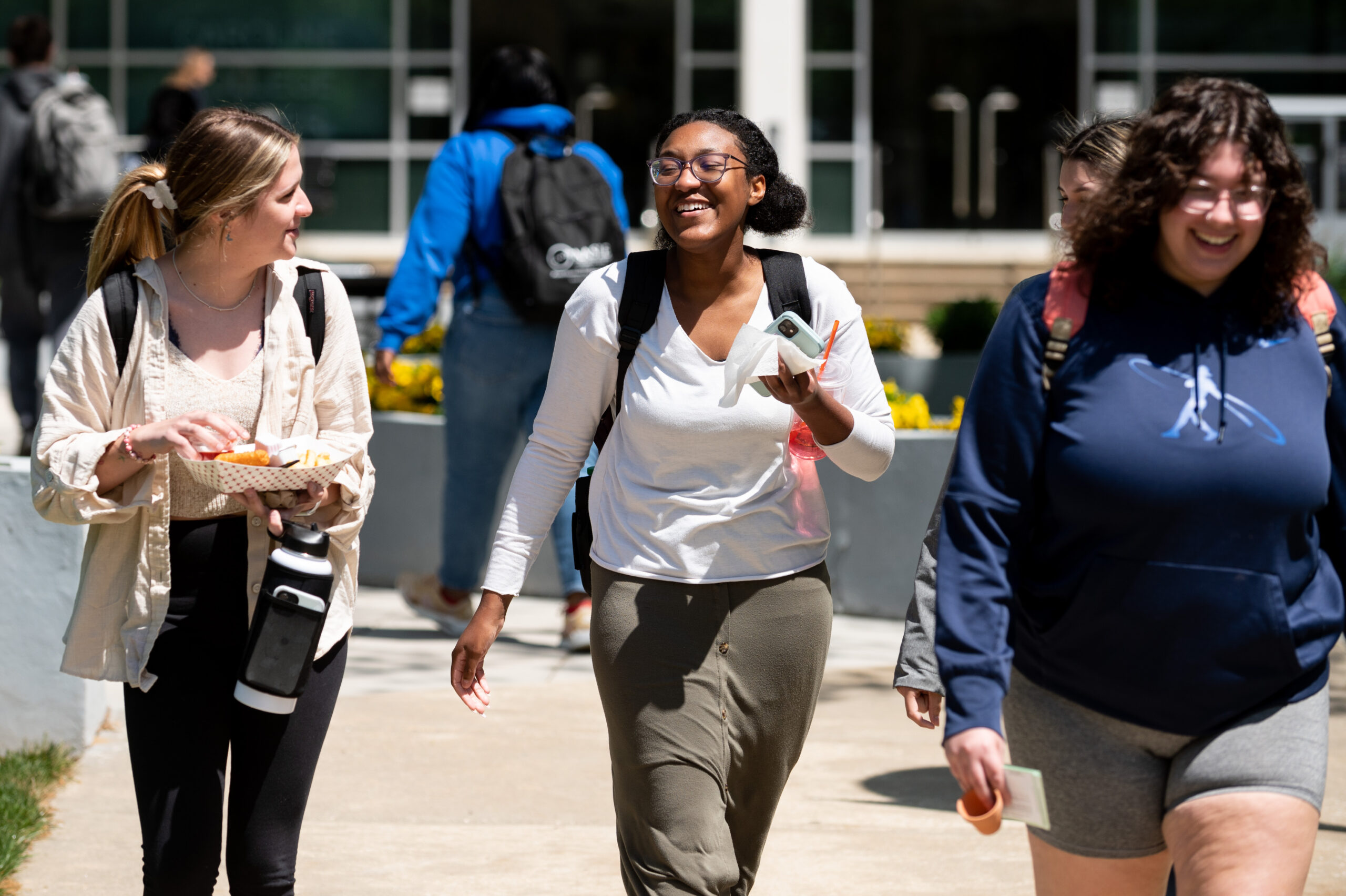 Three smiling students walking outside