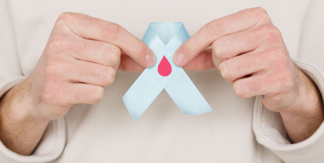 photo of a person's hands holding a folded blue ribbon with a red drop in the center