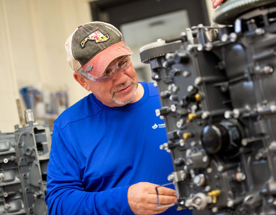 man wearing safety goggles works on outboard engine