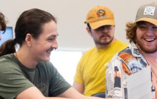 students smile at desks on computers